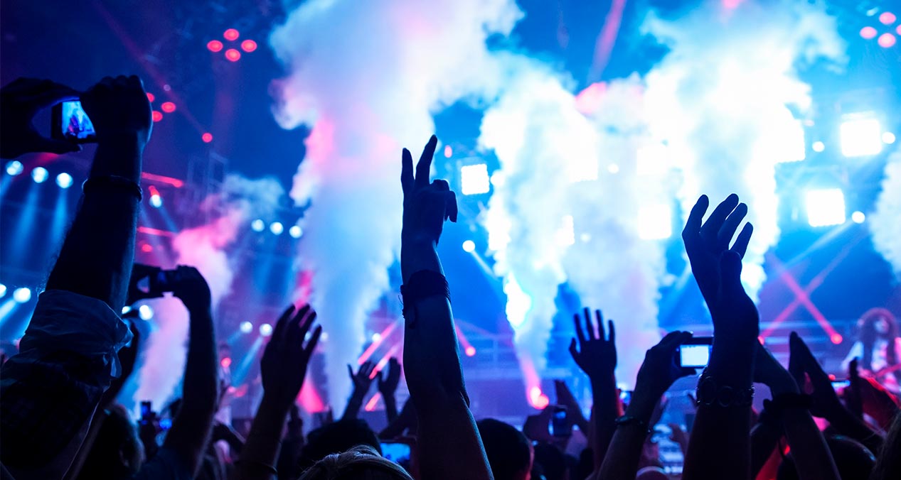 personas levantando las manos frente a un escenario en un concierto de música