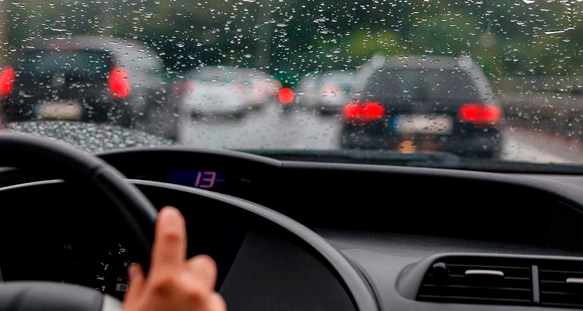 tablero de un automóvil y parabrisas con gotas de lluvia
