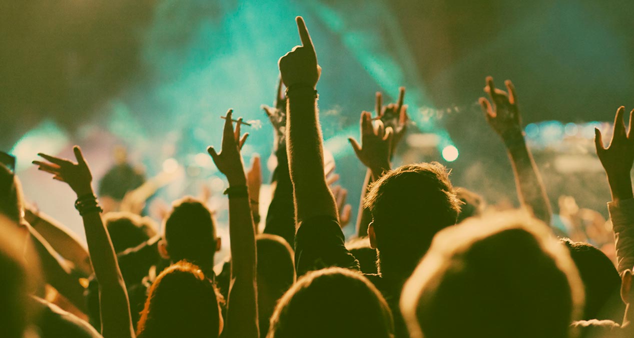personas levantando las manos frente a un escenario en un concierto de música