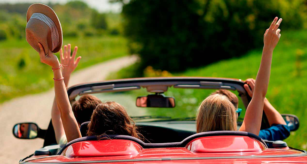 Auto convertible rojo con 4 jóvenes animados escuchando canciones para viajar en la carretera 