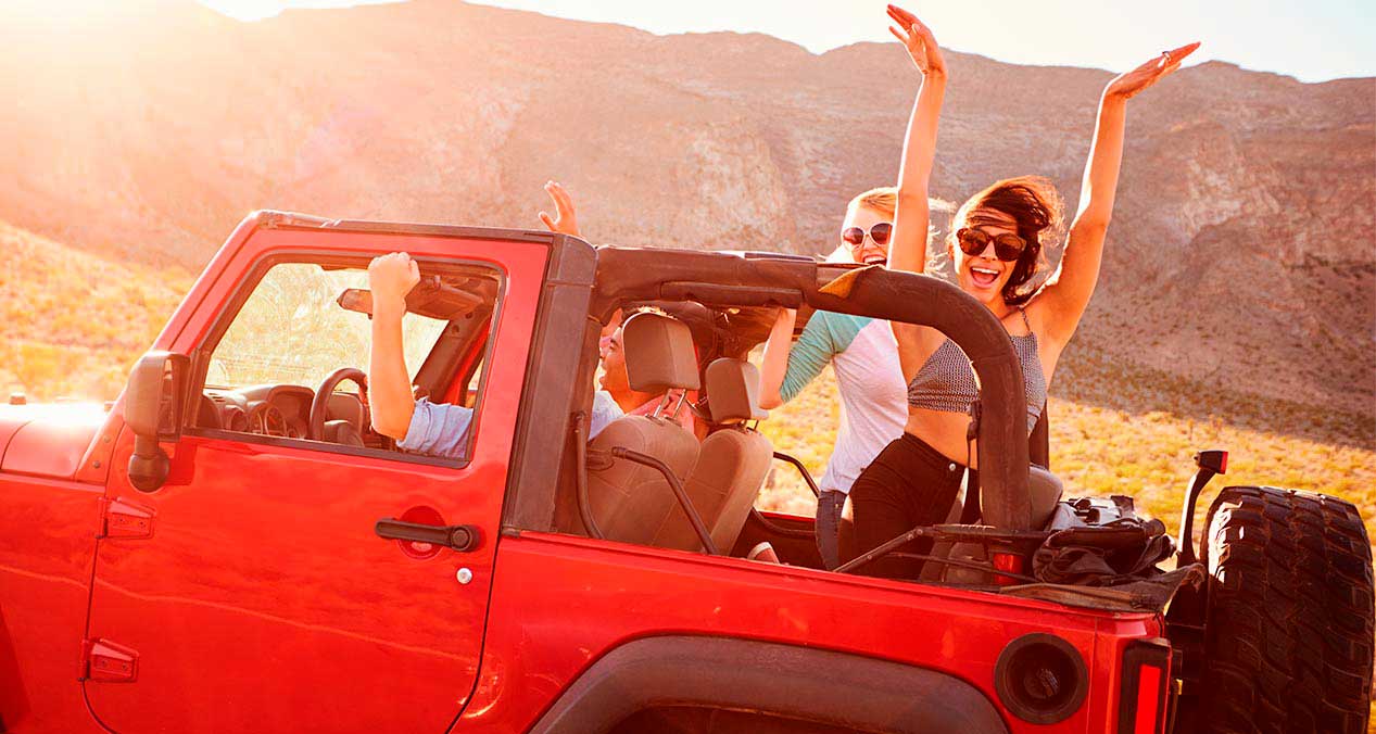 Viaje de amigos en una comioneta jeep rojo descapotable