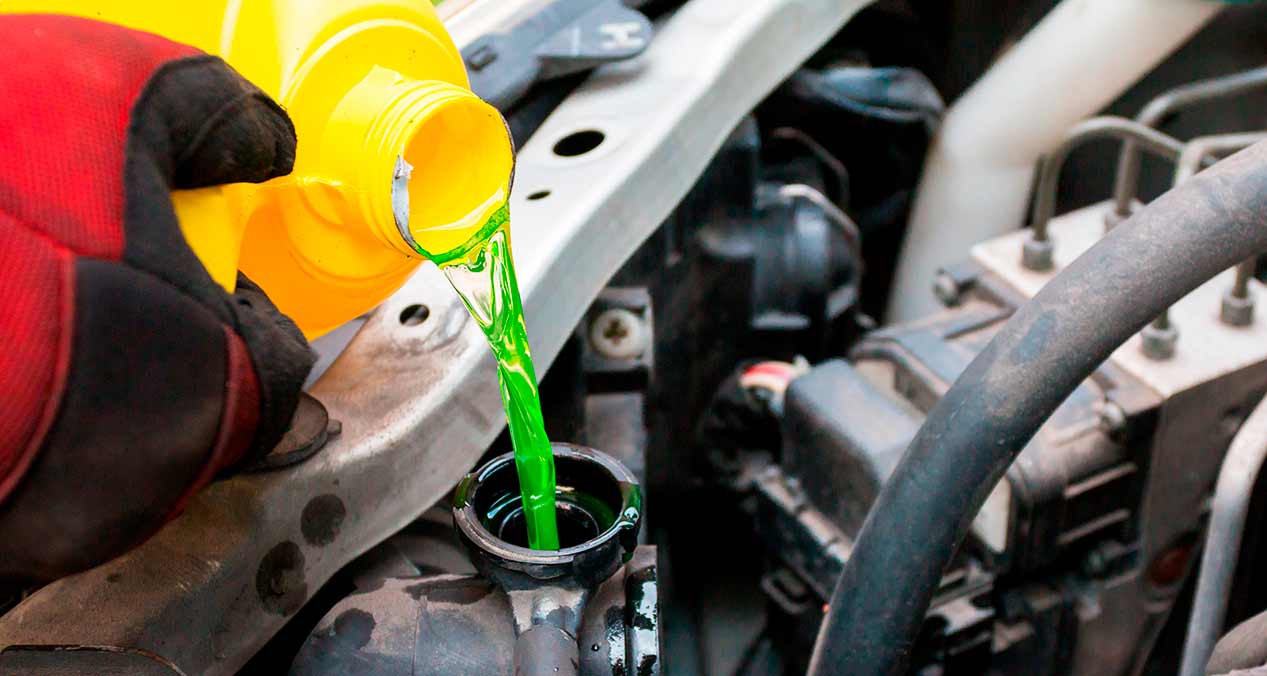 Liquido anticongelante verde es vertido en el motor de un auto desde un bote amarillo 